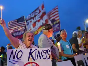Donald Trump smiling and gesturing humorously during a press event after being called a king by protesters